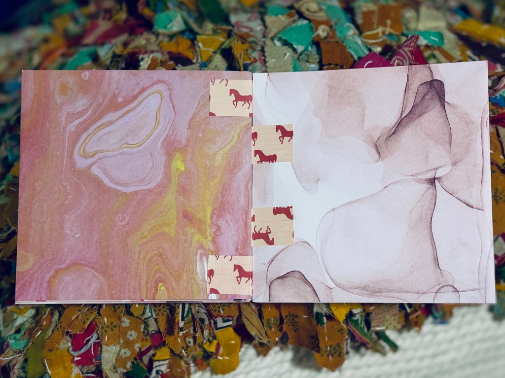 book open flat to show pink marbled pages and pink tabs with tiny pink horses on them
